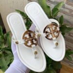 Tory Burch classic flat shoes in white, brown, and black with logo detail.