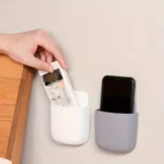 "Wall-mounted phone and remote holder storage box for smartphones, remote controls, and accessories"
