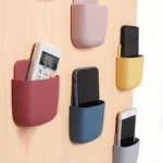 "Wall-mounted phone and remote holder storage box for smartphones, remote controls, and accessories"