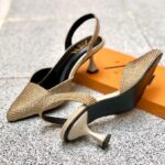 Close-up of a hand in a black glove holding a black Zara pointed-toe slingback heel, completely covered in black rhinestones/stones, with a low flared heel. A second heel and an orange Zara shoe box are visible in the background.