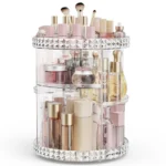 Clear acrylic $360^\circ$ rotating cosmetic organizer filled with various makeup brushes, perfumes, and skincare products, showing its adjustable multi-tiered design.