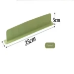 Flexible silicone sink baffle plate/splash guard in a kitchen sink, shown attached to the edge to prevent water and oil from spraying onto the counter.